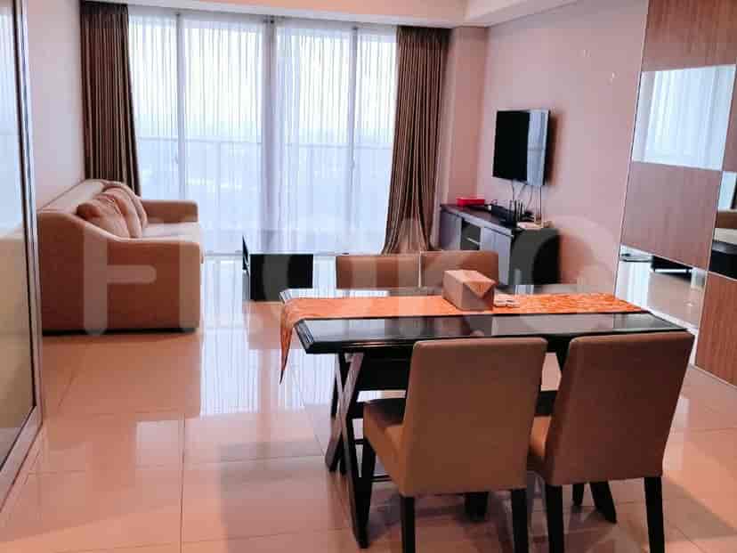 A dining area adjacent to the living room, featuring a glass-top dining table with chairs and a TV console.
