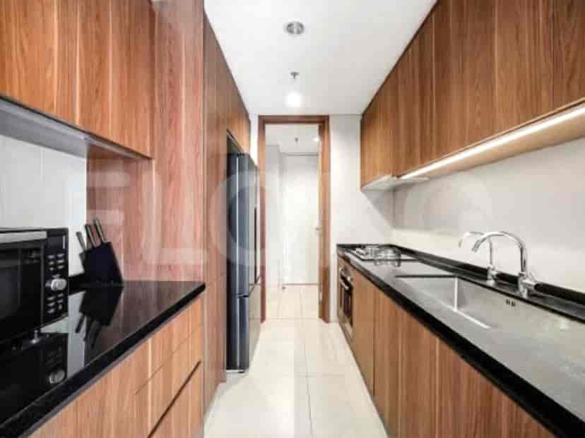 A long, narrow kitchen with wood-paneled cabinets, black countertops, and built-in appliances.