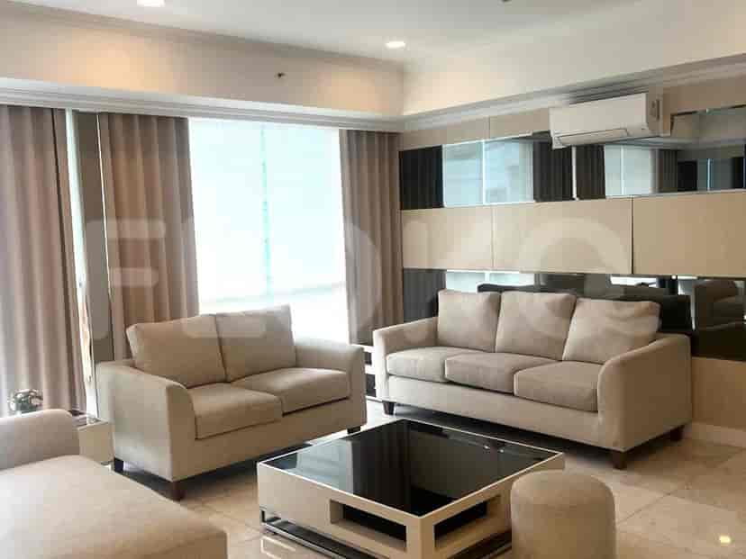 A modern living room with a beige sofa set, a glass-top coffee table, and mirrored wall paneling.