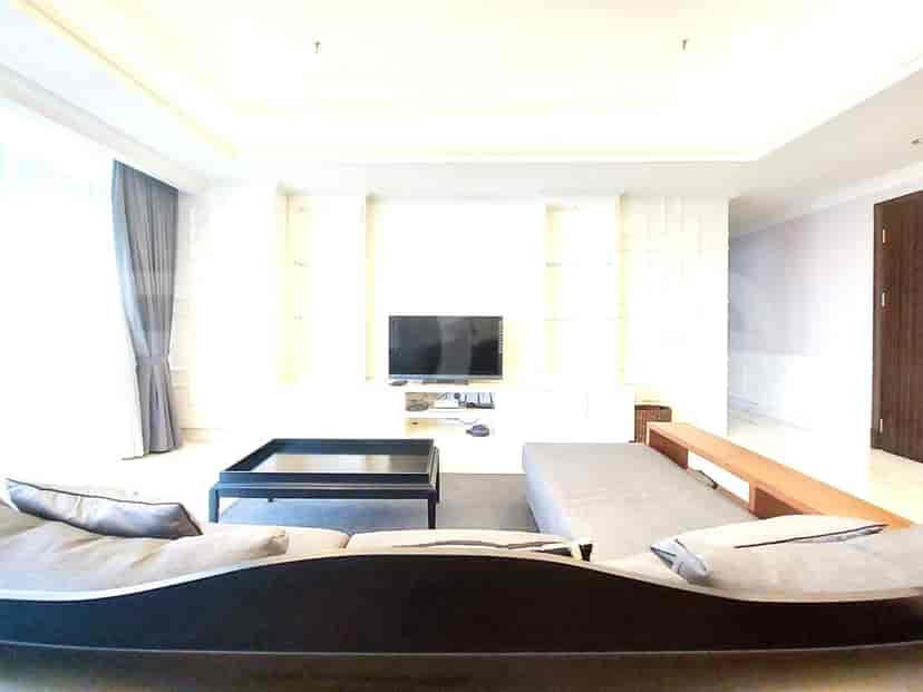 A living room with a sectional sofa, a large TV, and built-in shelving.