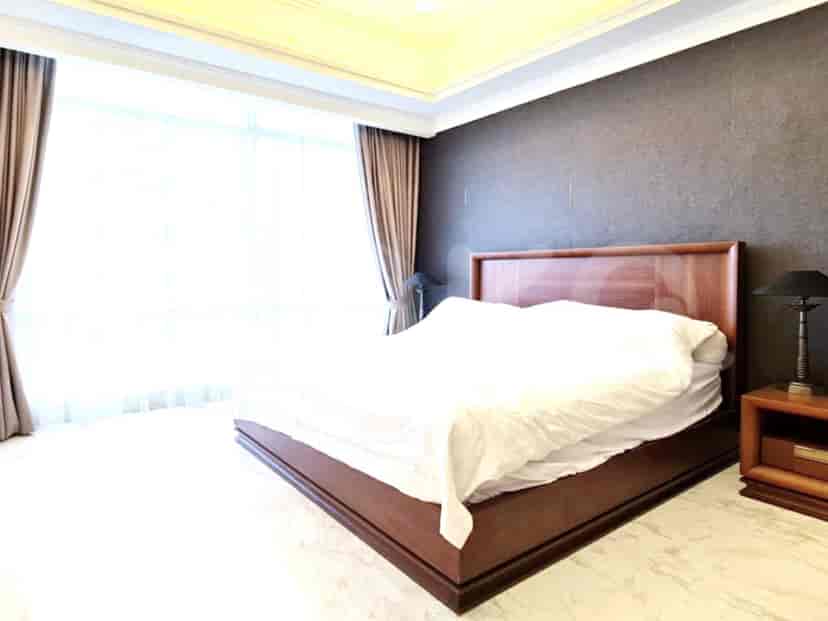 A bedroom with a wooden bed frame, white bedding, and a large window with curtains.