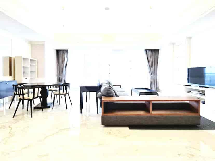 A spacious living and dining area with marble floors, a round dining table, a long sofa, and a TV console.