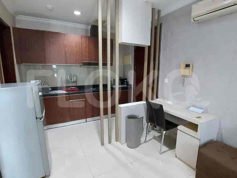 A kitchen area with dark wood cabinets, a refrigerator, and a small desk.