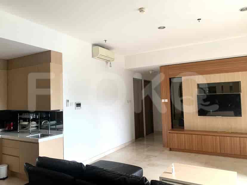 Area tamu terbuka dengan dapur modern, meja makan, dan sofa, mengarah ke unit hiburan TV.