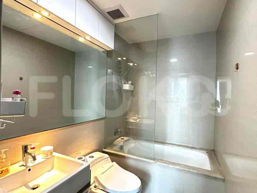 A modern bathroom with a bathtub, toilet, and sink, featuring grey tiled walls.