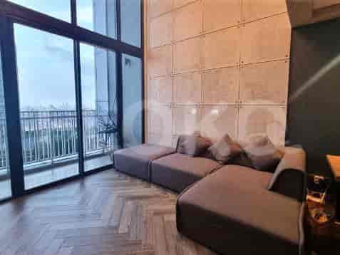 A sectional sofa in front of a textured concrete wall with large windows.