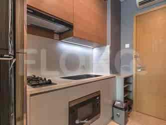 A compact kitchen with wooden cabinets, a stove, a microwave, and a sink.