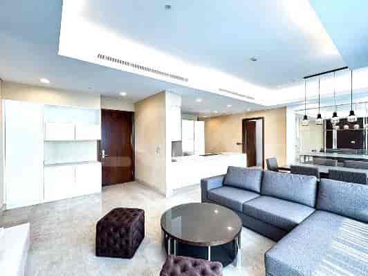 Spacious living room with a sectional sofa, ottoman, coffee table, and integrated kitchen.