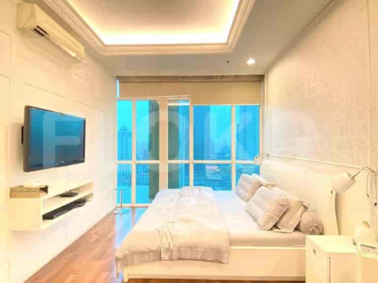 A master bedroom with a king-size bed, wall-mounted TV, and a large window with a city view.