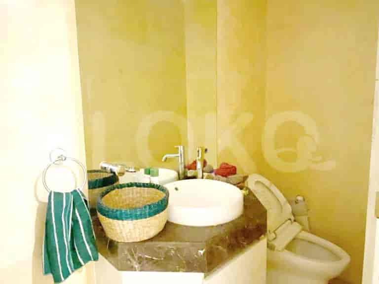 A compact bathroom featuring a wall-mounted sink, toilet, and textured walls.