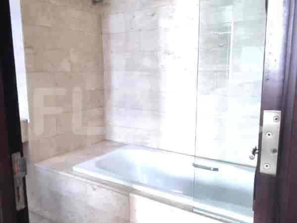 A bathroom with a bathtub and a glass shower screen, surrounded by marble tiles.