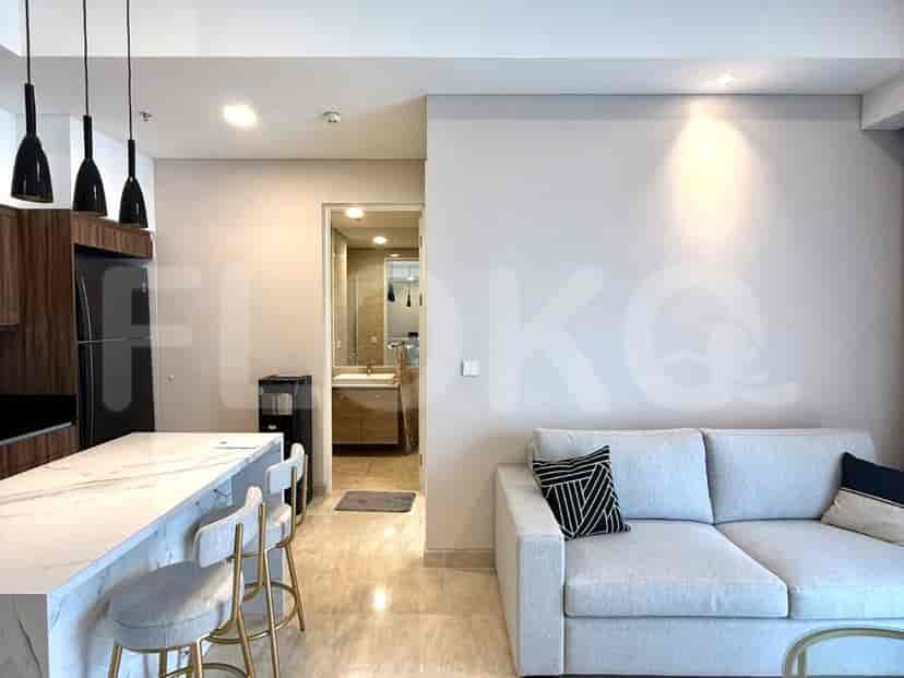 An open-plan living room and kitchen area with a sofa, kitchen island, and refrigerator.