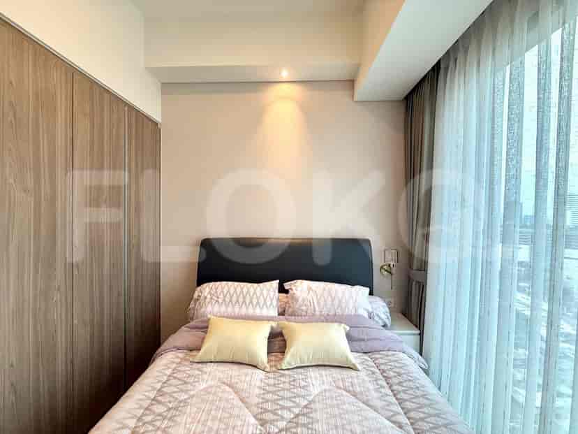 A bedroom with a bed, wooden wardrobe, and large window with curtains.