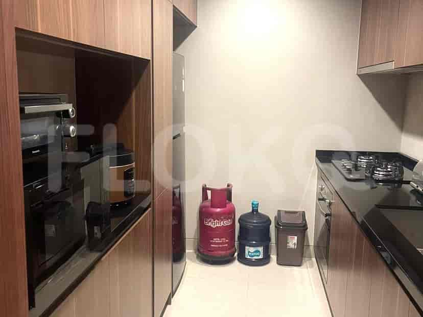 A compact kitchen with gas stoves, a refrigerator, and cooking gas cylinders.