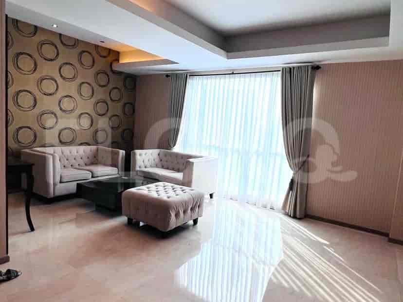 Sebuah ruang tamu modern yang menampilkan sofa berumbai, meja kopi gelap, dan jendela besar dengan tirai tipis.