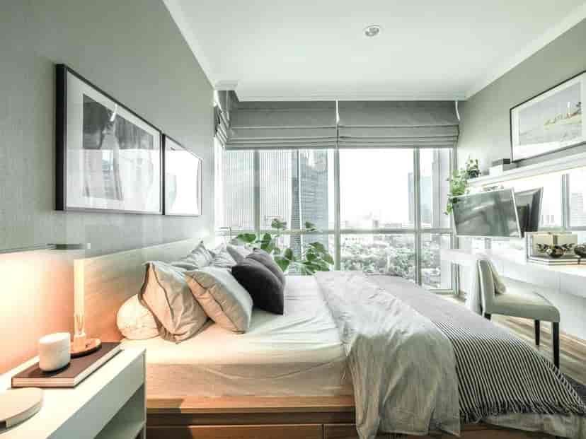 A bedroom with a queen bed, large window with city view, and a desk.