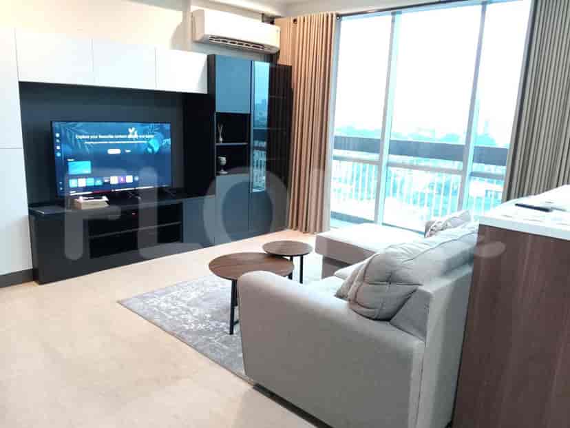 A cozy living room featuring a sectional sofa, a coffee table with two smaller tables, and a wall-mounted television.