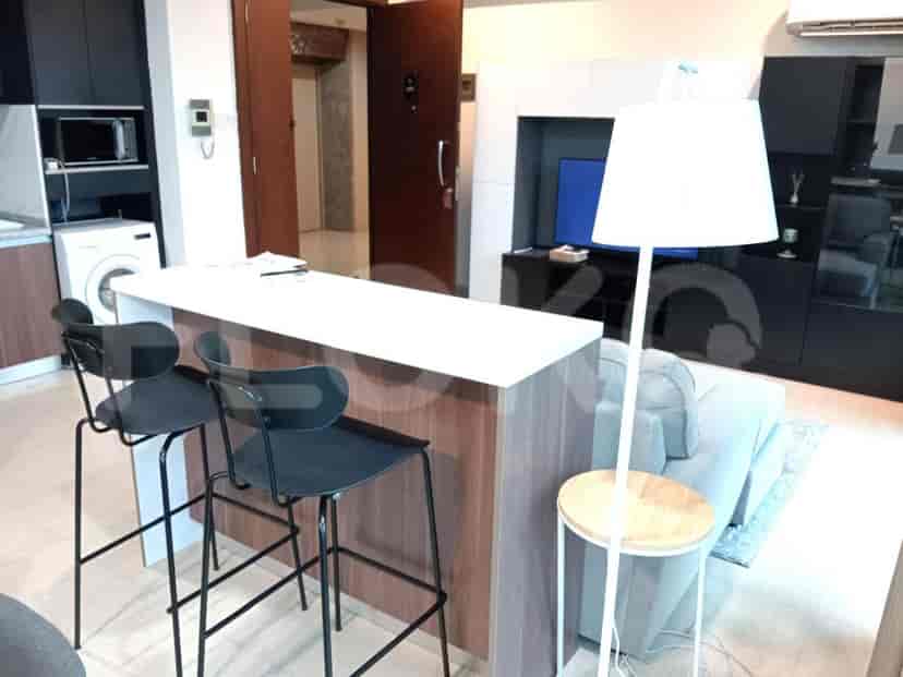 A modern kitchen area featuring a breakfast bar with stools, a washing machine, and a microwave.