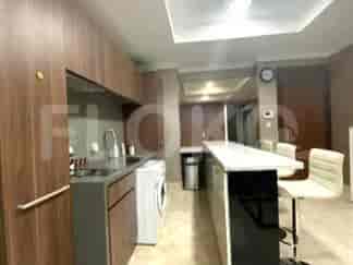 Dapur terbuka modern dengan kabinet kayu, meja, dan kursi bar.