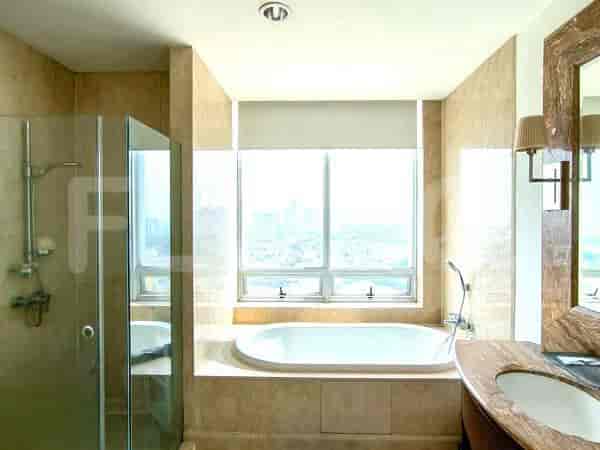 Kamar mandi mewah yang menampilkan bak mandi freestanding, shower terpisah berkaca, dan meja rias dengan countertop marmer.