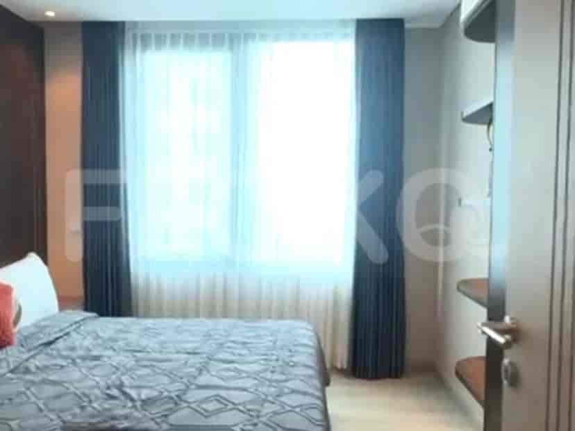 A cozy bedroom featuring a queen-size bed, bedside table, and a window with curtains.