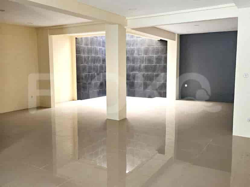 An empty interior room with tiled floors, cream walls, and a dark tiled accent wall.