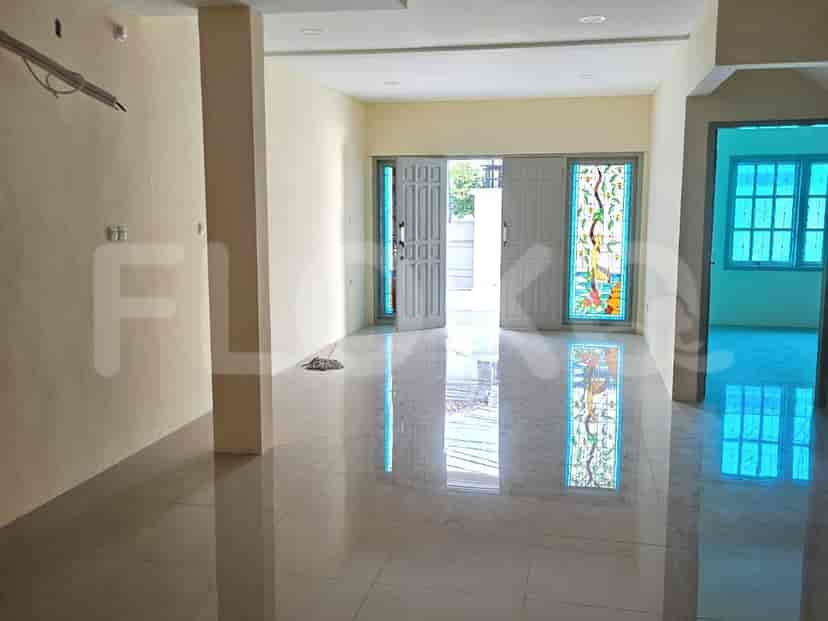 A spacious, empty living room with tiled floors, cream walls, and large double doors.