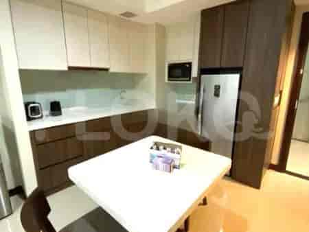 A compact kitchen with white and dark wood cabinets, a refrigerator, microwave, and a dining table.