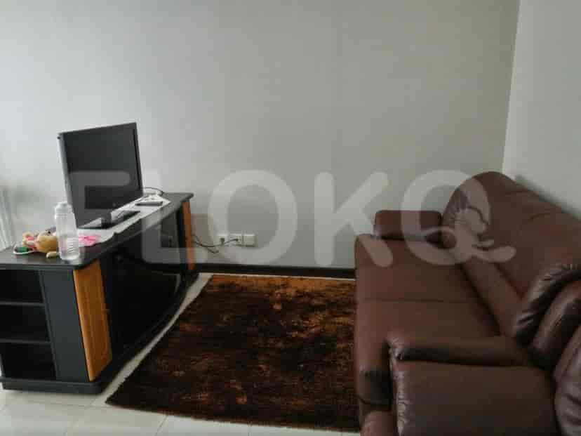 Ruang tamu dengan TV, sofa, dan karpet.