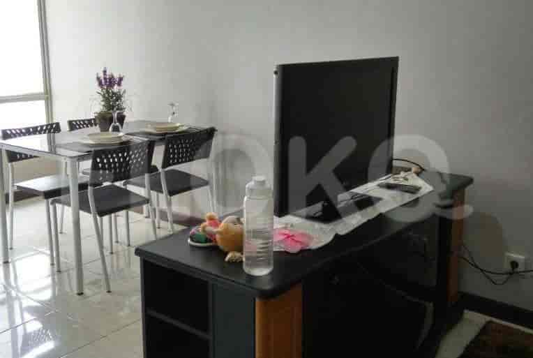 Area gabungan ruang tamu dan ruang makan dengan meja makan, konsol TV, dan sofa.