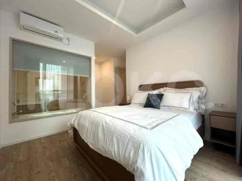 A bedroom with a large bed, bedside table, and a window with blinds.