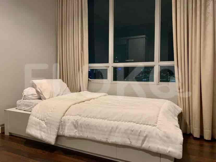 Cozy bedroom with a bed, large windows, and beige curtains.