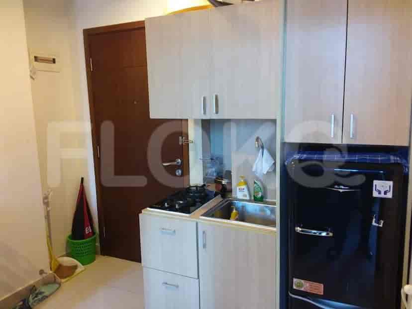 Compact kitchen with cabinets, stove, and refrigerator.
