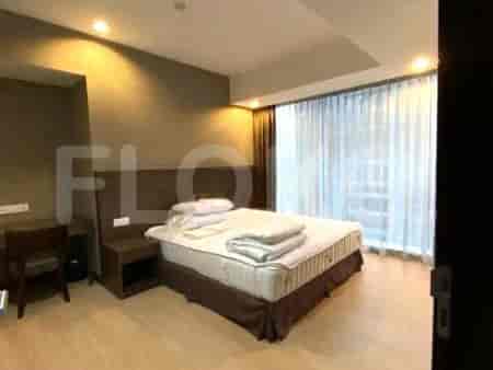 A bedroom with a bed, bedside tables, and a desk, with large windows and curtains.