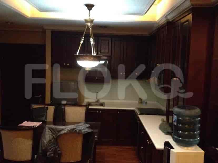 Dapur dengan lemari gelap, meja makan, dan pencahayaan di atas kepala.
