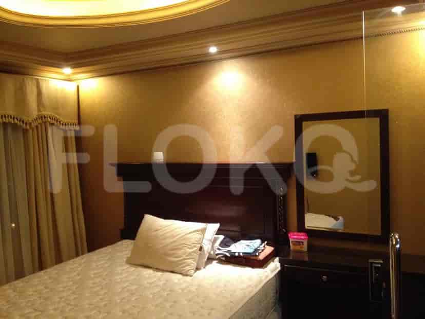 Kamar tidur dengan tempat tidur ganda, cermin, dan meja samping.