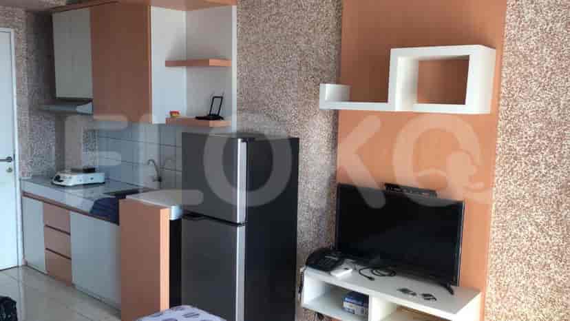 A compact kitchen area with cabinets, refrigerator and cooking area.