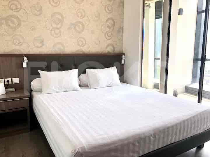 A bedroom with a large bed, nightstand, and access to a balcony.