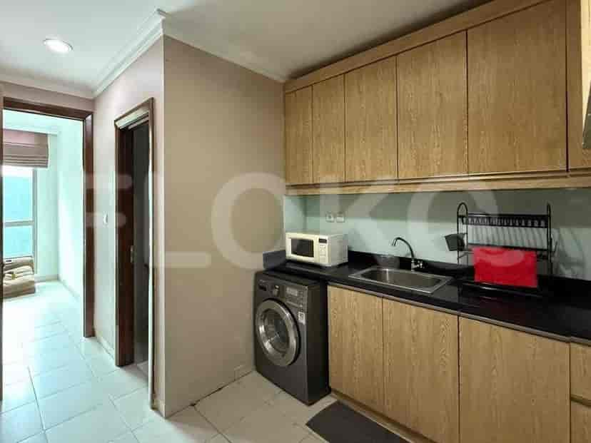 A compact kitchen with wooden cabinets, a stainless steel sink, a microwave, and a washing machine.
