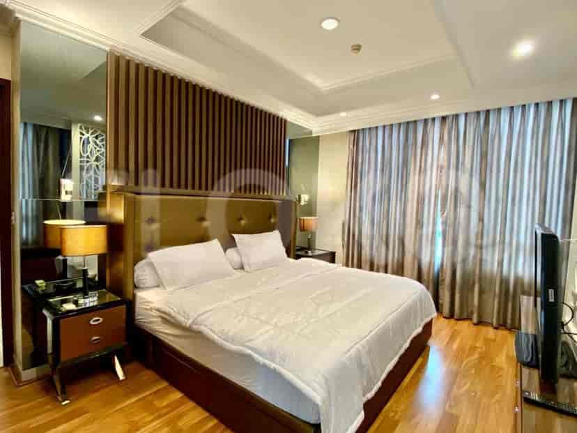 A bedroom with a king-size bed, mirrored wall, and dark curtains.