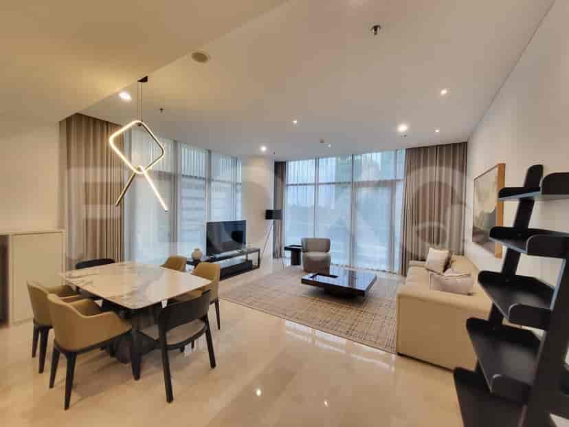 A spacious open-plan living and dining area with a dining table for six, a large sofa, a coffee table, and a TV console.