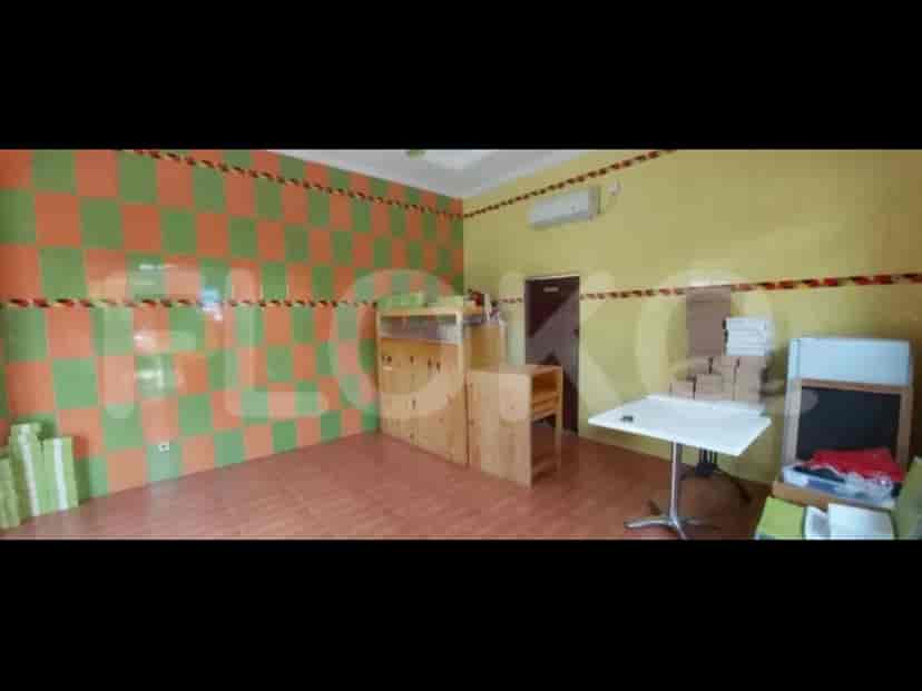 A room with green and orange checkerboard wall panels, a table, and cabinets.