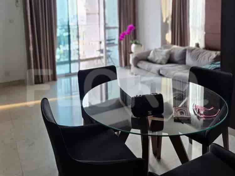 A glass-top dining table with four black chairs and a black handbag, sunglasses, and two boxes on top.