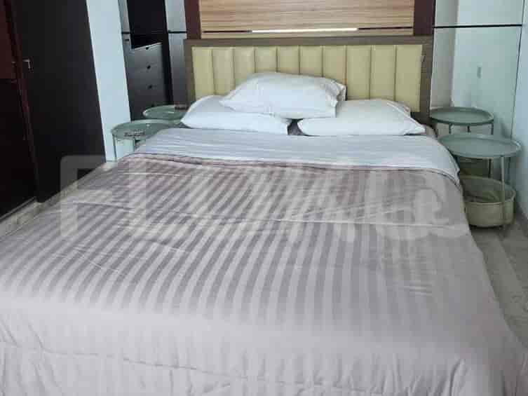 A bedroom with a queen-size bed, striped comforter, and headboard with cushioned panels.