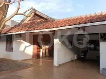 Bagian luar depan rumah dengan atap genteng, dinding putih, dan carport tertutup.
