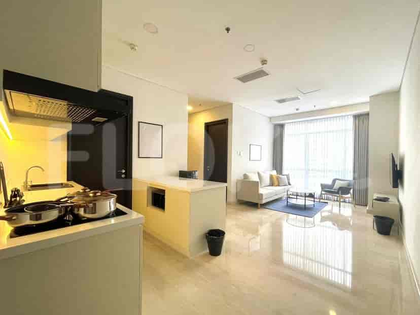 A spacious living and kitchen area with a sofa, armchair, and a modern kitchen.