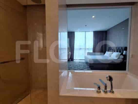 A luxurious bathroom with a bathtub, a separate shower stall, and a vanity area visible through a glass partition.
