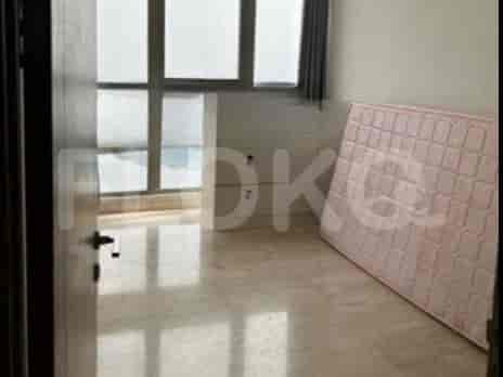 An empty room with a mattress on the floor and large windows.