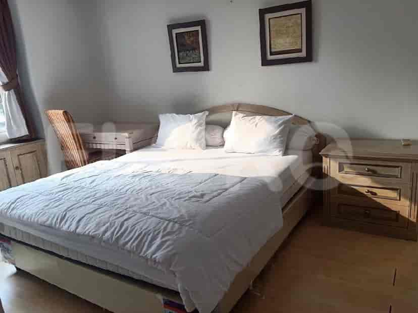 A bedroom with a queen-sized bed, bedside tables, a desk, and artwork on the wall.