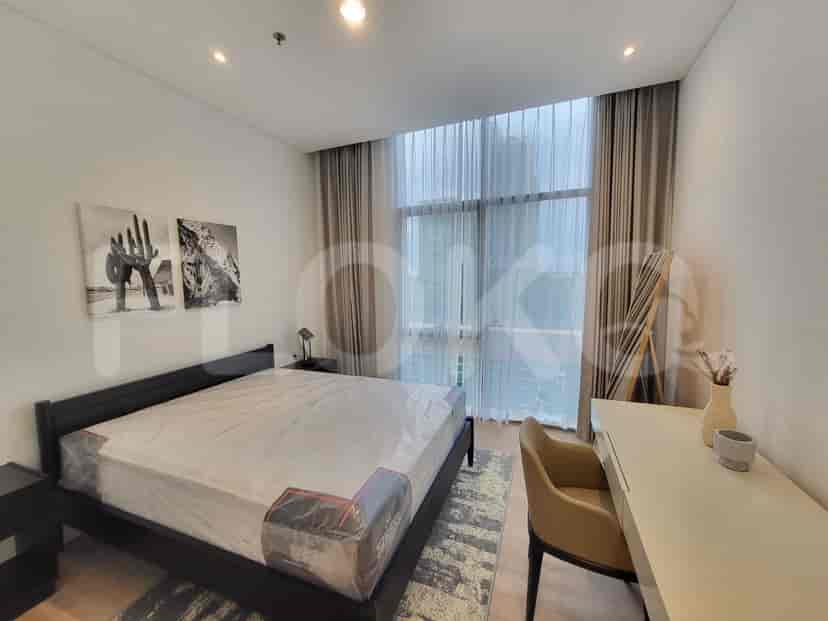 A bedroom with a king-size bed, a desk with a chair, and a large window.